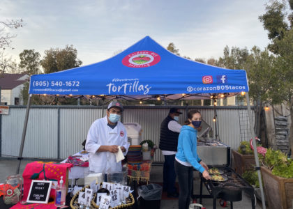 Corazon 805 Tacos operates an outdoor kitchen under a blue pop-up tent branded with their logo.