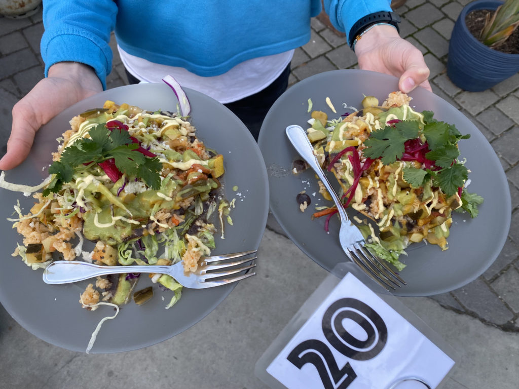 Two plates of vibrant calabazita, or squash medley, tostadas topped with sauces, pickled onion and cilantro.