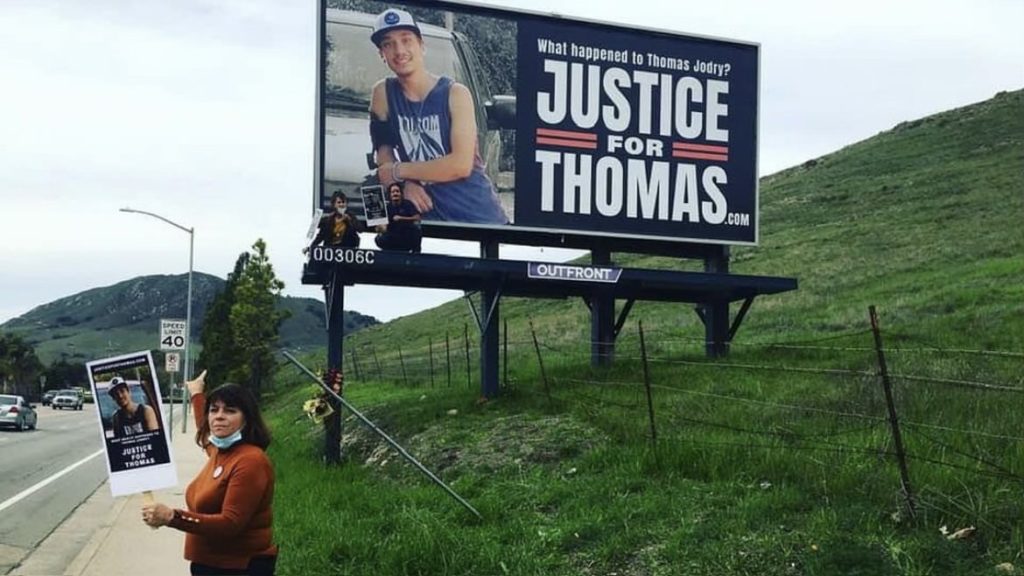 Mary Jane, mother of Thomas Jodry, stands in front of billboard promoting JusticeforThomas.com.  